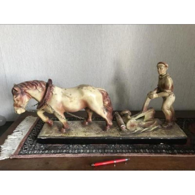 Mooi gipsenbeeld van ploegend paard en boer.